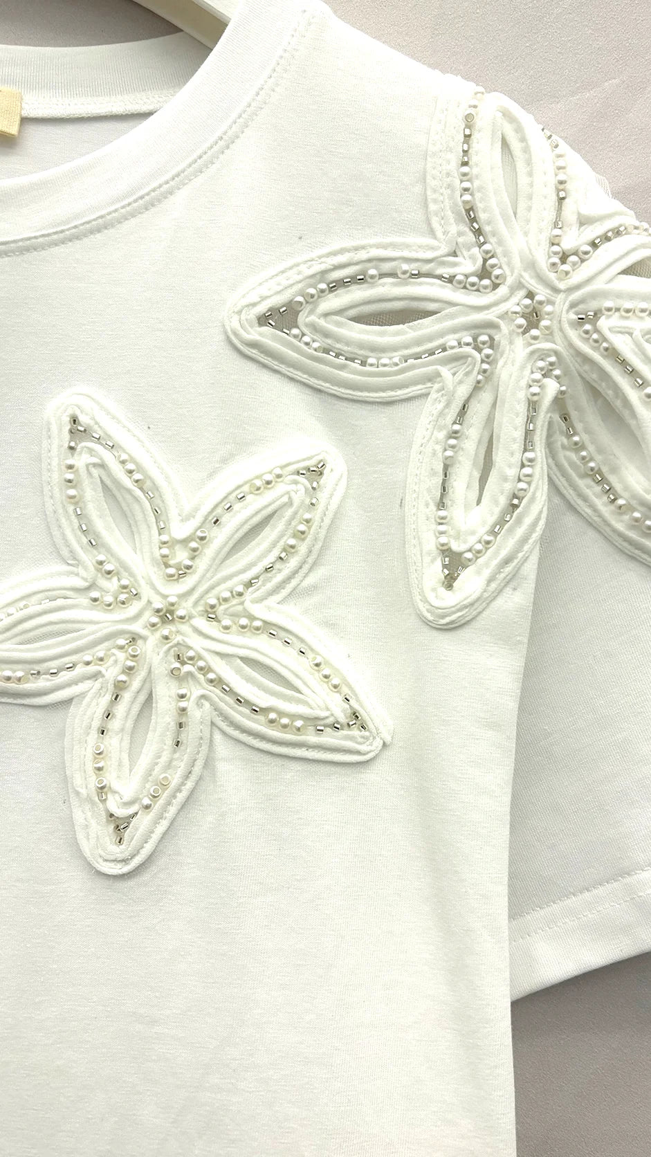 	Close-up of embroidered flower and laser-cut eyelet cutwork detail on t-shirt