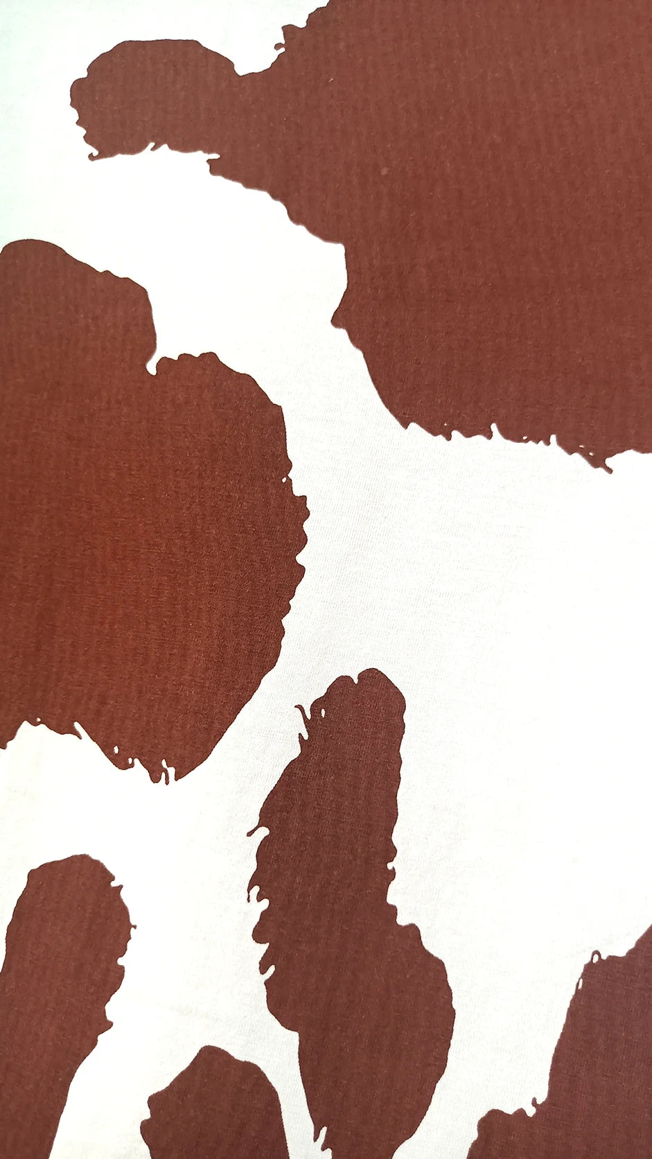 Close-up of brown and white cow print spotted pattern detail on t-shirt