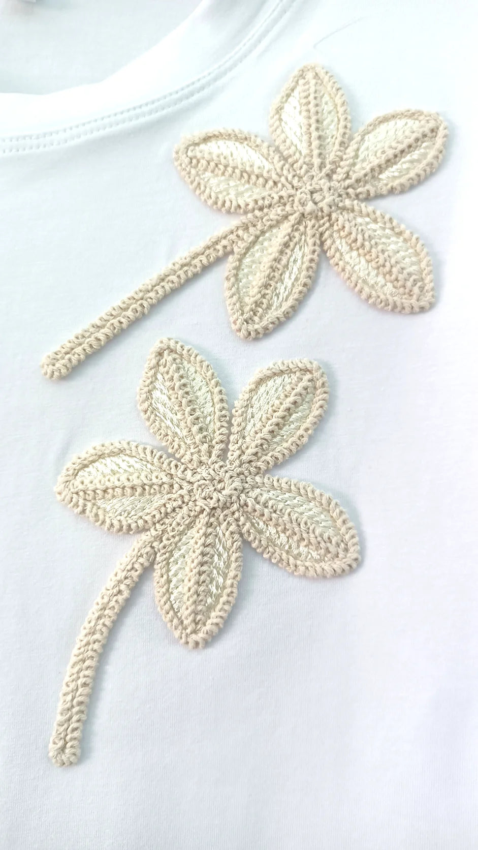 Close-up of handcrafted beaded 3D flower embroidery on t-shirt showing sculptural texture